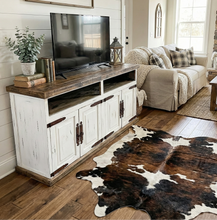 Load image into Gallery viewer, Living room with white entertainment console, beige sofa, and cowhide rug.
